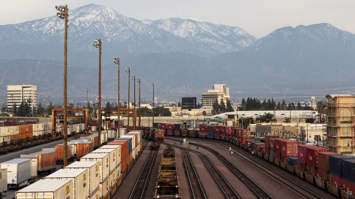 Snow-covered mountains loom in the background above the San Bernardino rail yard, which has some the the worst air quality in the area. A plan by Southern California air regulators would rely on voluntary measures from rail yards and ports to limit harmful emissions.
