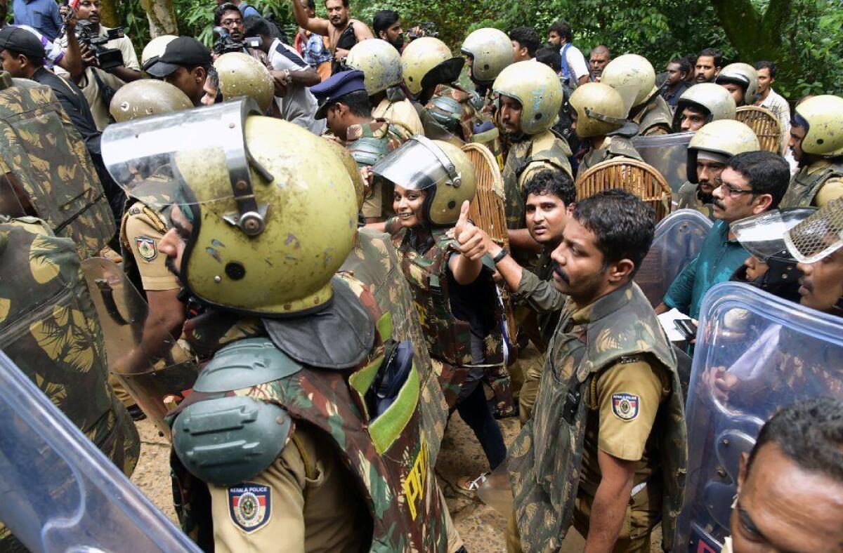 Indian journalist Kavitha Jakkal, wearing protective gear, is flanked by police near the Sabarimala temple.