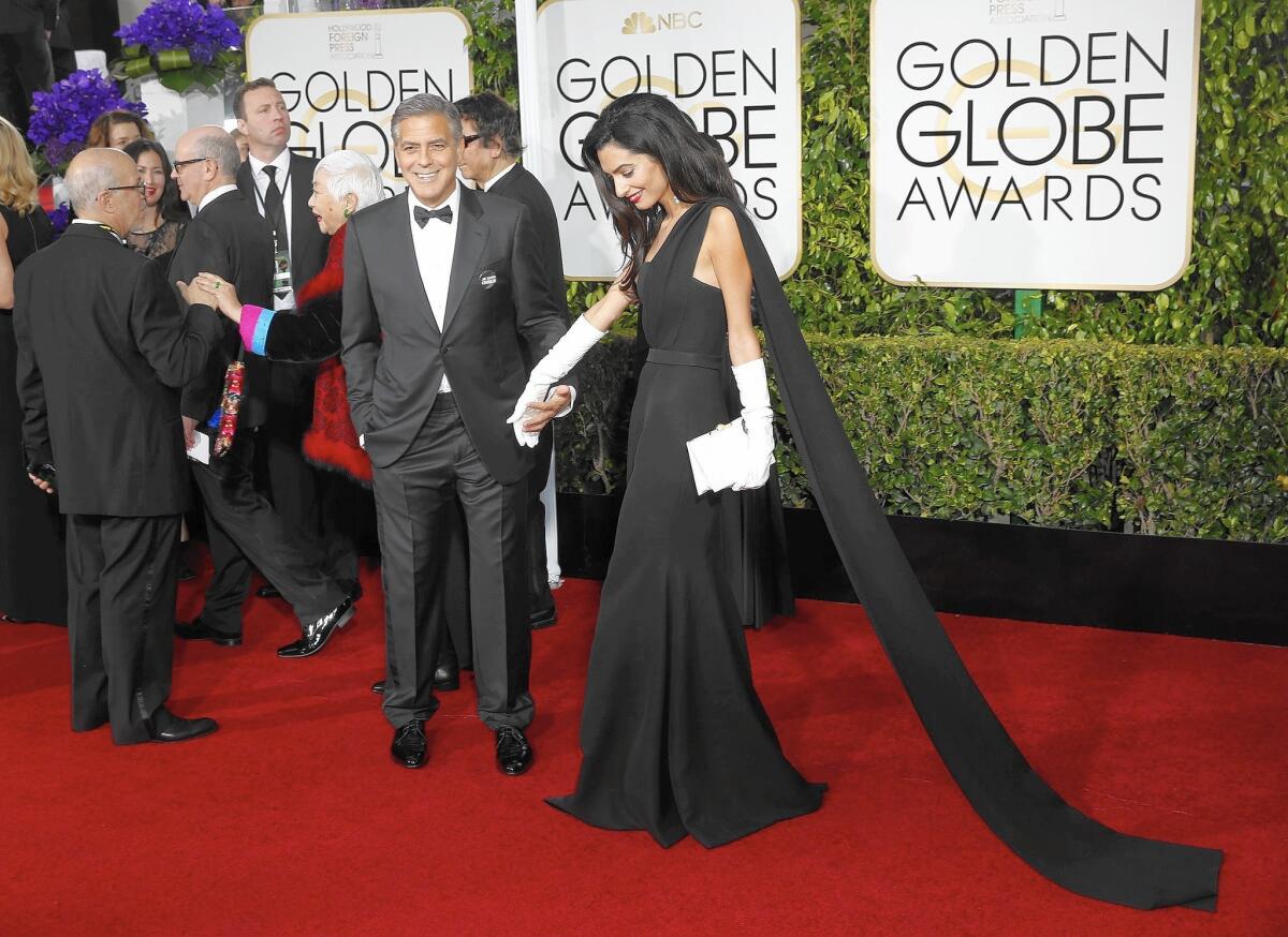 Amal Clooney, with her husband George, sports white gloves with her Dior gown.