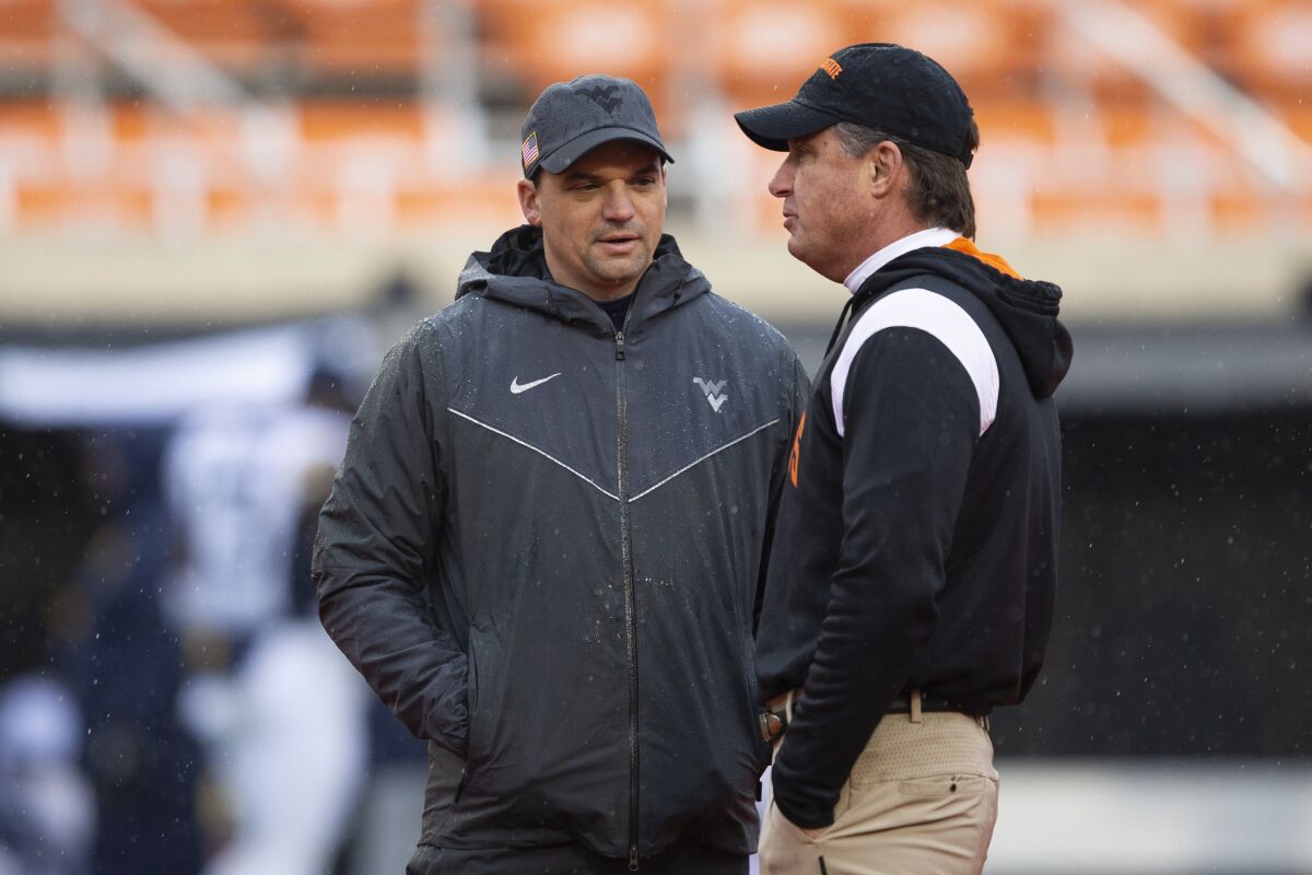 West Virginia head coach Neal Brown and Oklahoma State head coach Mike Gundy talk to each other before the NCAA college football game in Stillwater, Okla., Saturday Nov. 26, 2022. (AP Photo/Mitch Alcala)