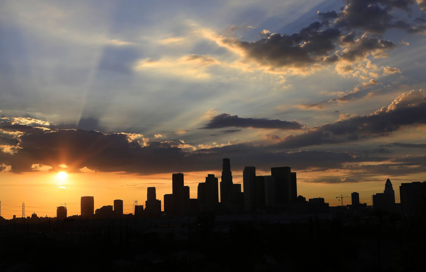 The setting suns sets clouds aglow as they pass over the Los Angeles skyline.