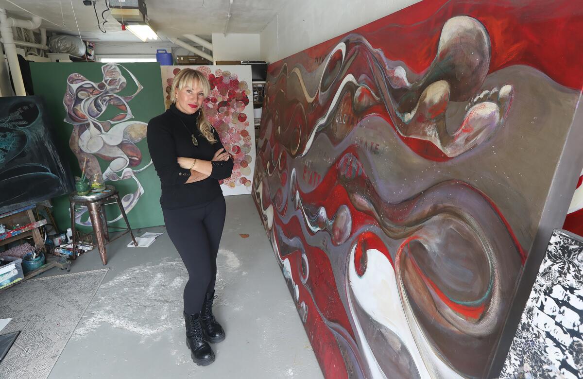 Local artist Christiana Lewis Ulwelling stands next to her painting on a 14-foot-by-6-foot canvas.