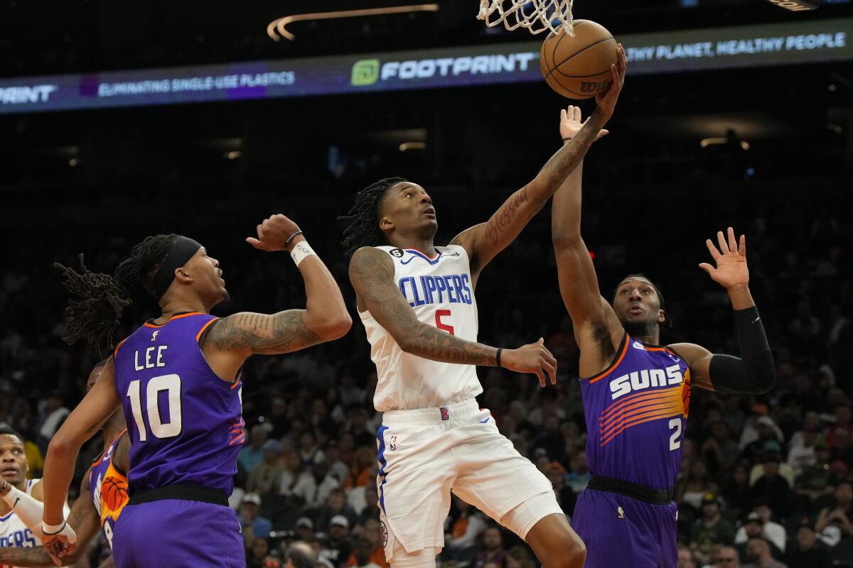 Clippers guard Bones Hyland splits the defense of Suns guard Damion Lee, left, and forward Josh Okogie for a layup.