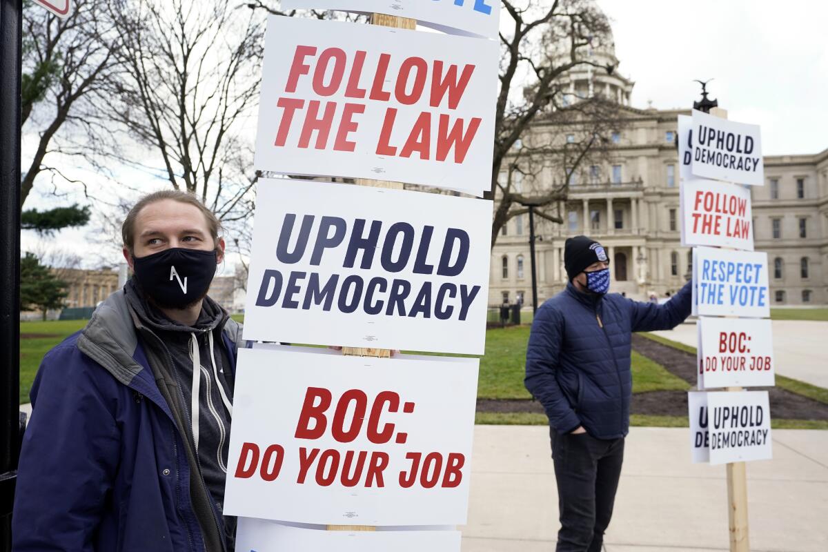 Joscha Weese, left, stands outside the Capitol building during a rally in Lansing, Mich.