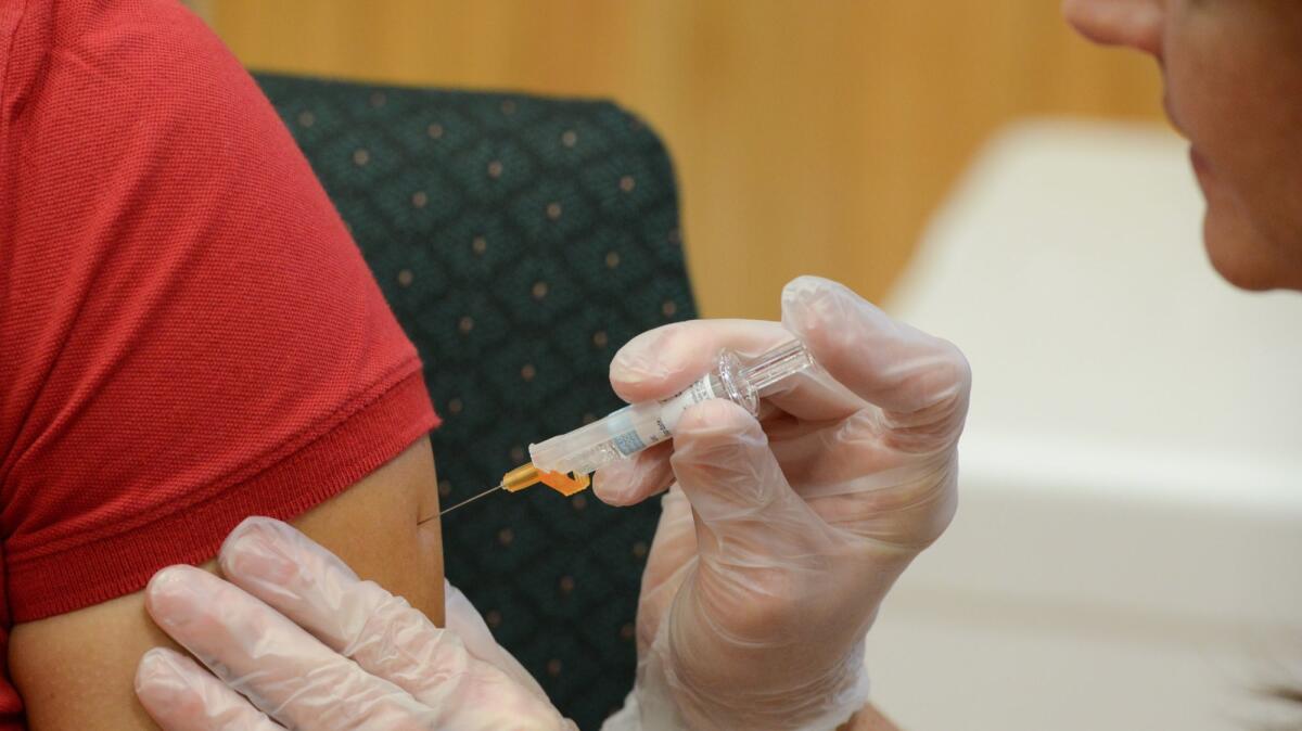 A woman receives a flu vaccine shot at a community fair in September.