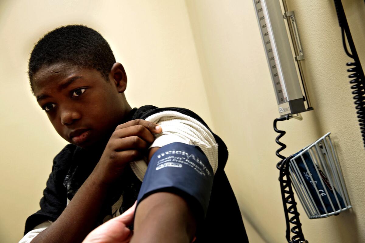 At Capitol City Family Health Center, Isaac Williams, 14, gets his blood pressure taken during a physical. The eighth-grader hopes to join the basketball team at school.