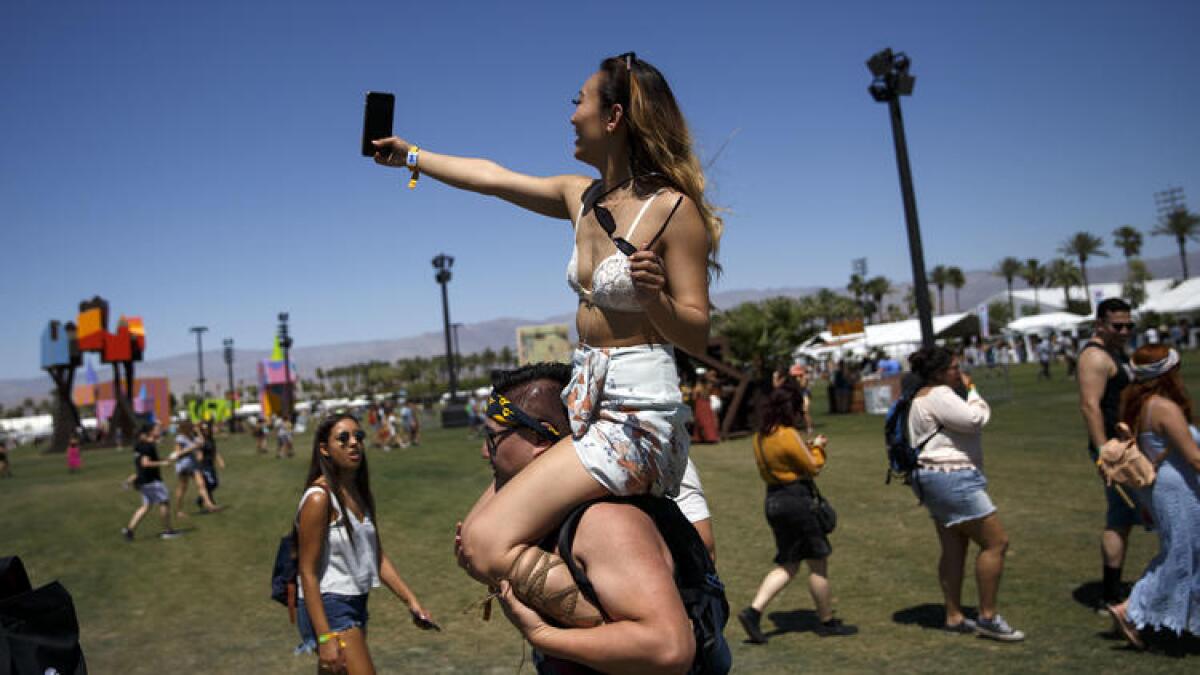 Barbara Huynh of San Jose takes a selfie while atop the shoulders of Anthony Seto of Los Angeles on Friday at Coachella.