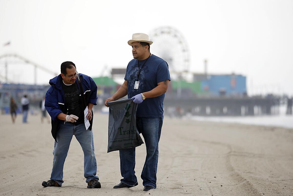 L.A. County employees Jesus Garcia, left, and Jerry San Martin pick up cigarette butts and other small pieces of trash along the Santa Monica shoreline as part of Cesar Chavez Week activities across Southern California.