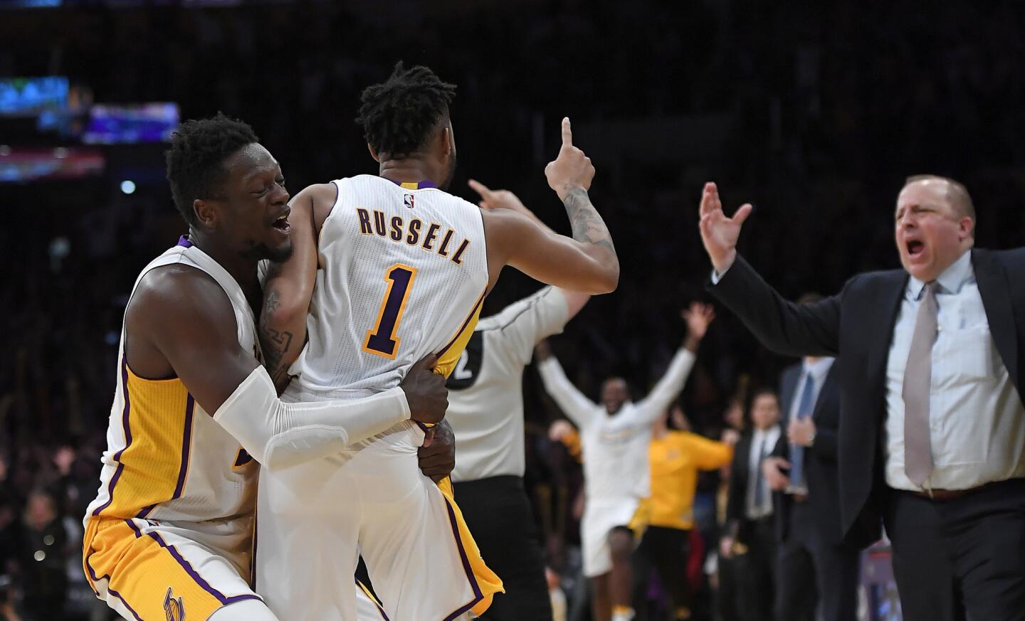 Los Angeles Lakers guard D'Angelo Russell, center, is hugged by forward Julius Randle, left, after hitting a game-winning three point shot as Minnesota Timberwolves Coach Tom Thibodeau reacts during the second half.