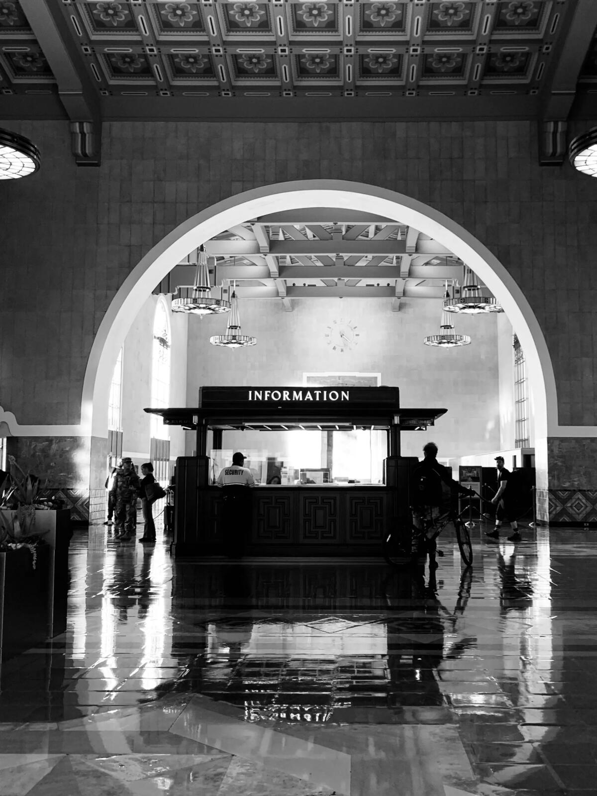 A black and white photo shows a kiosk within a cavernous, tiled space.