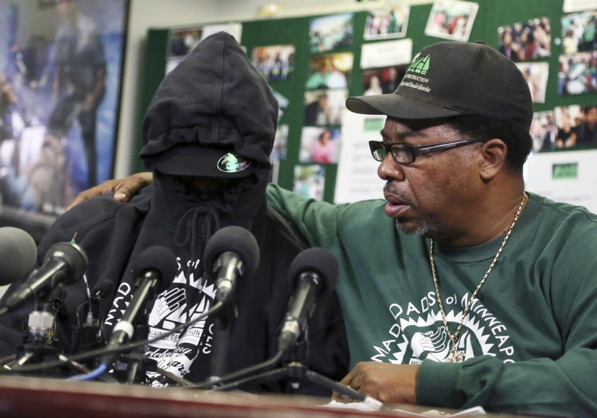 The father, left, of a 9-year-old plane stowaway talks to reporters in Minneapolis. He covered his face to protect his identity. At right is V.J. Smith, a supporter of the family.