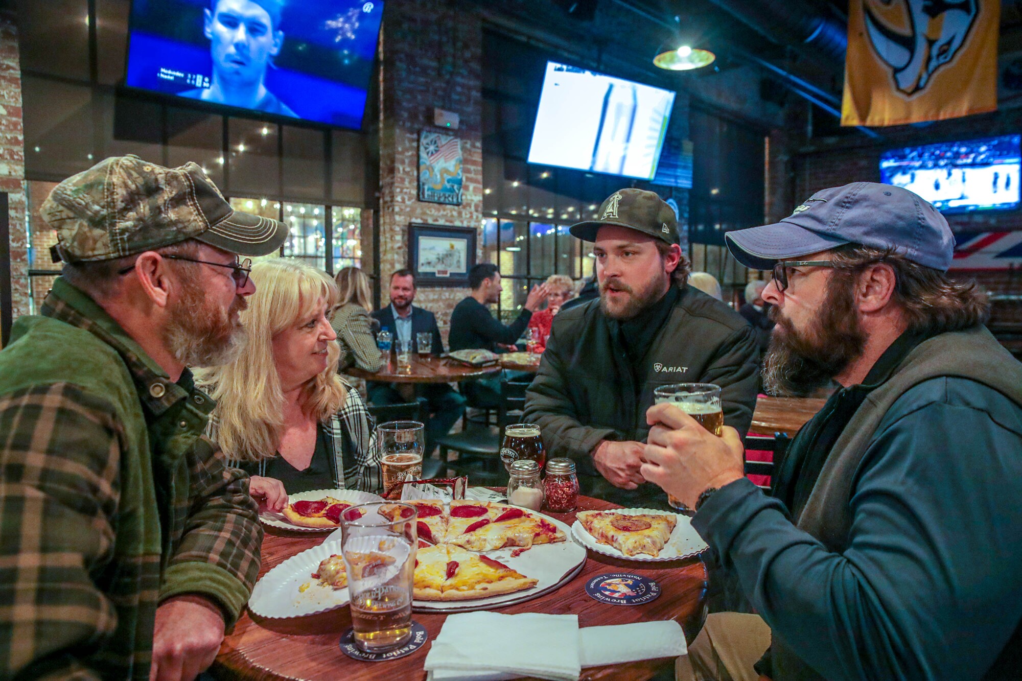 Four people talk and eat at a brewery.