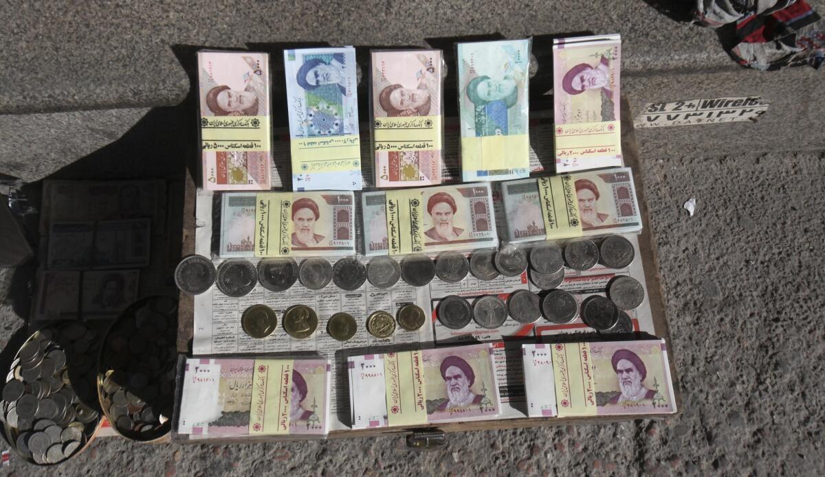 A sidewalk money vendor in Tehran displays foreign coins and Iranian currency, which has lost almost half its value because of Western sanctions.