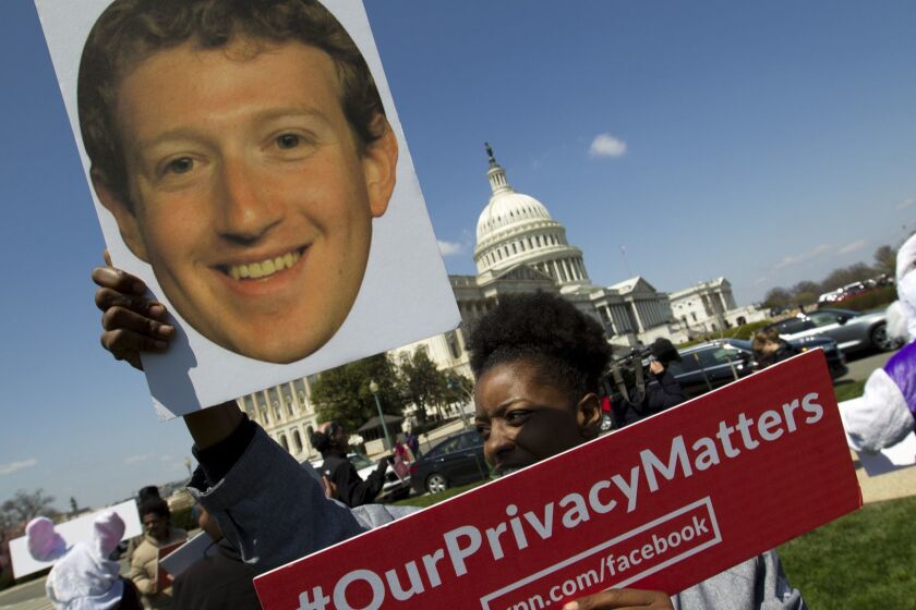 Demonstrator holding up a photo of Facebook CEO Mark Zuckerberg protest outside of the U.S. Capitol in Washington, Tuesday, April 10, 2018, ahead of Zuckerberg's appearance before a Senate Judiciary and Commerce Committees joint hearing. (AP Photo/Jose Luis Magana)