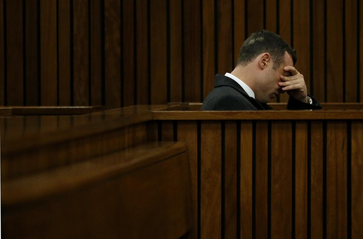 Oscar Pistorius, accused of murdering his girlfriend, Reeva Steenkamp, covers his face during his trial at the North Gauteng High Court in Pretoria.