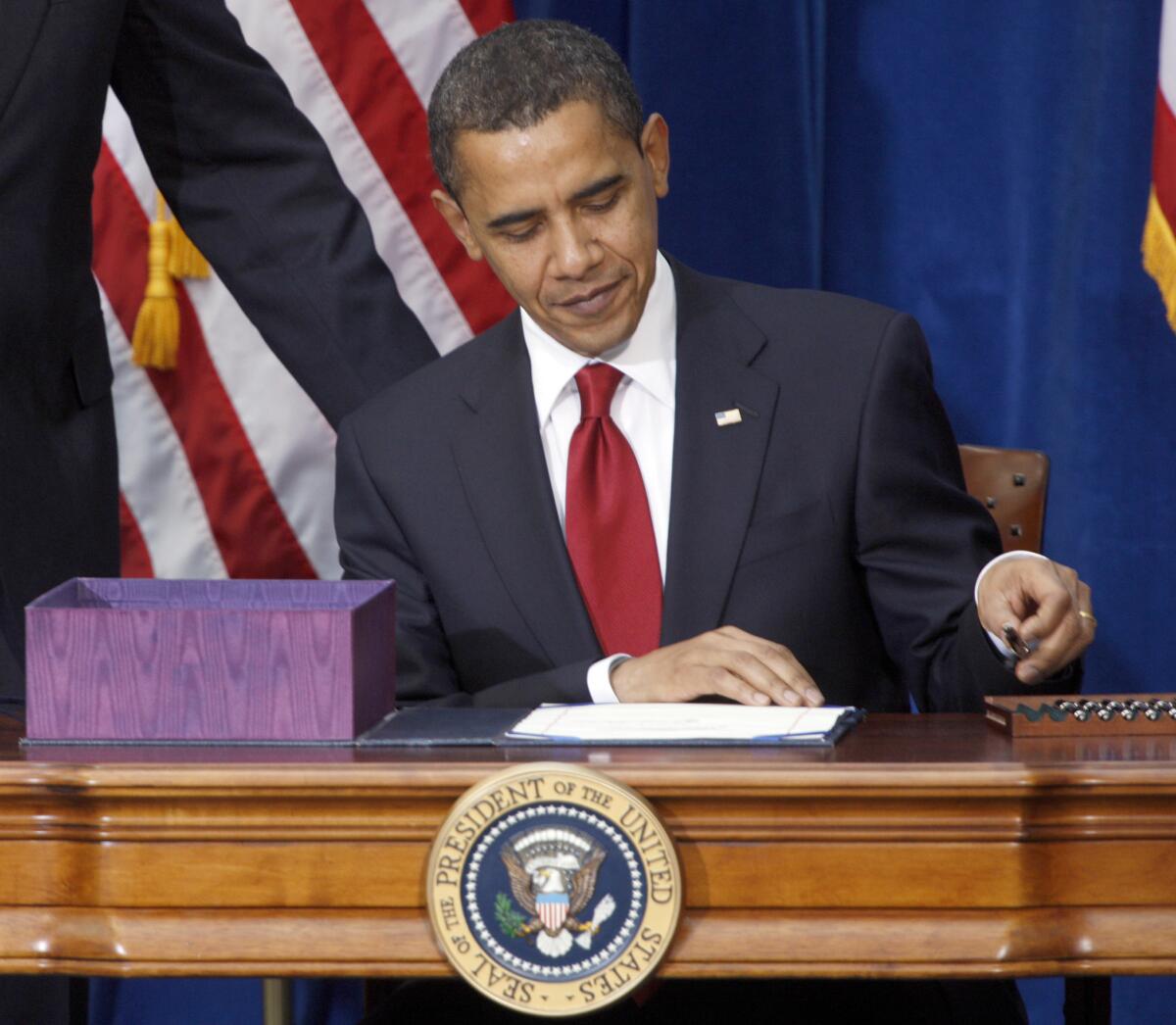 President Obama, in a file photo, picks up a pen to sign the economic stimulus bill.