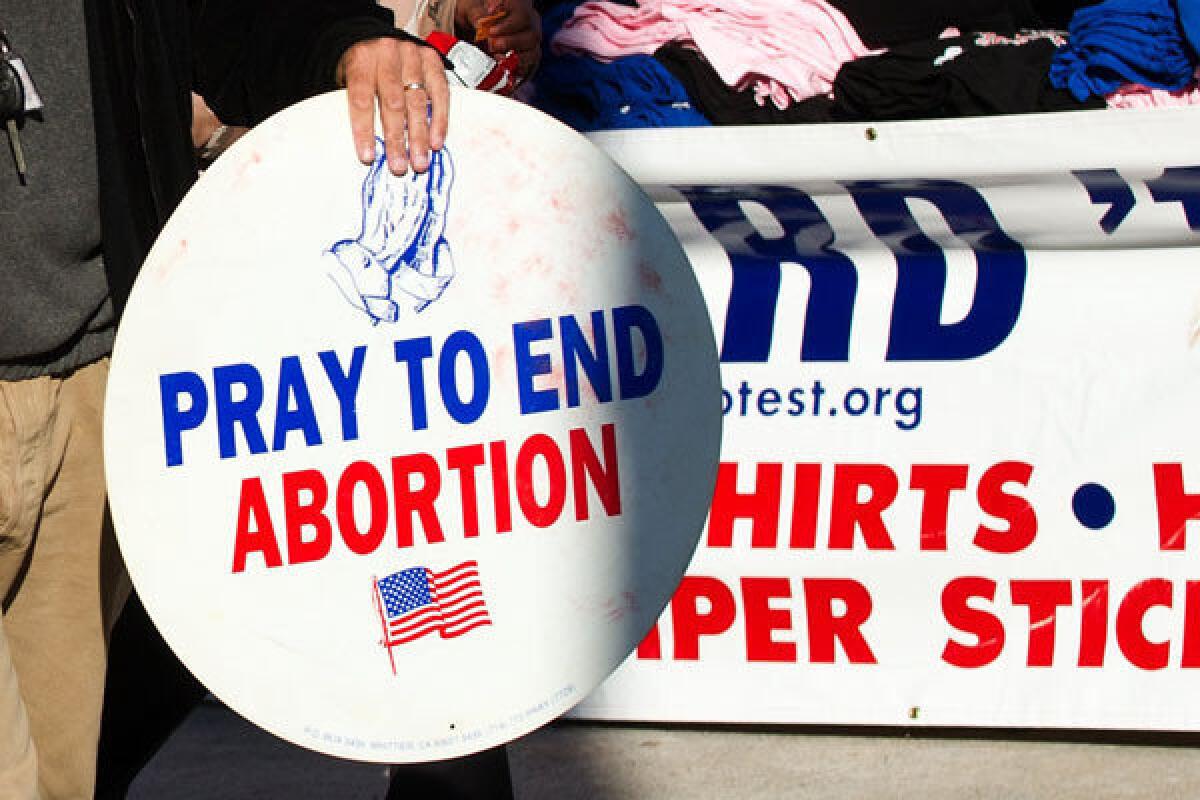 An antiabortion protester holds signs at Centre College in Danville, Ky.