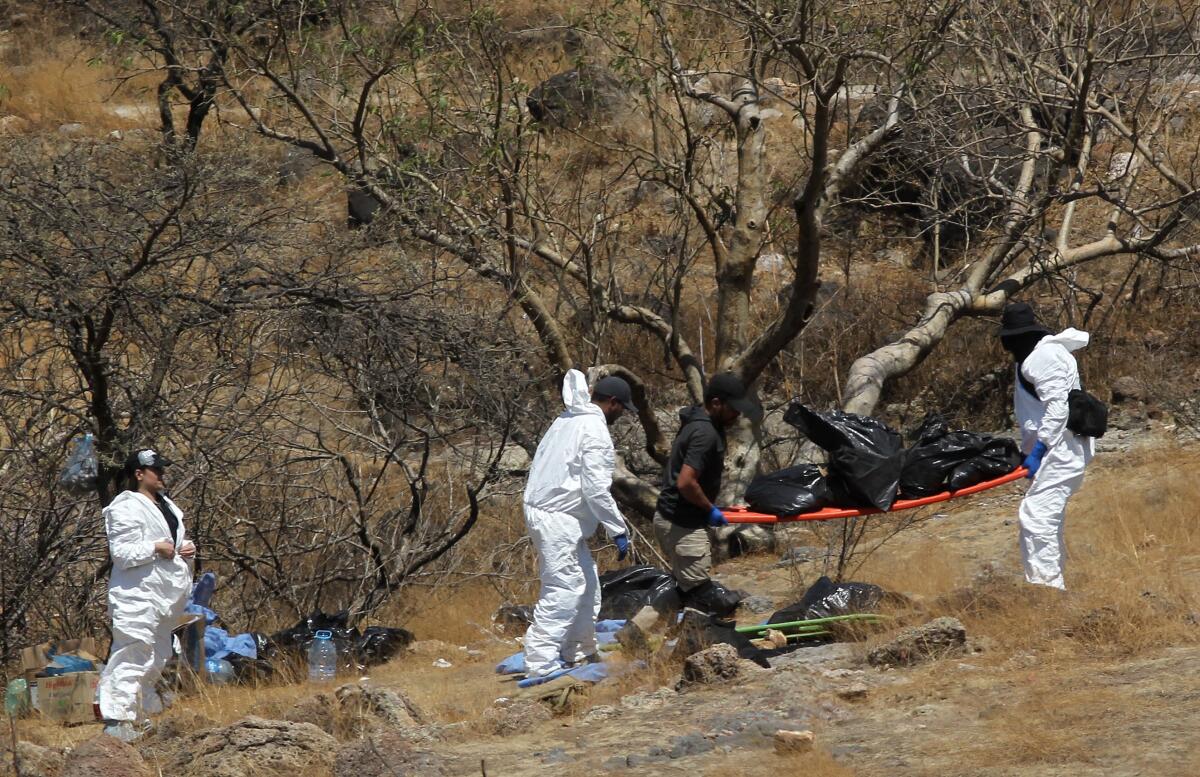People in protective gear work with plastic bags of human remains.