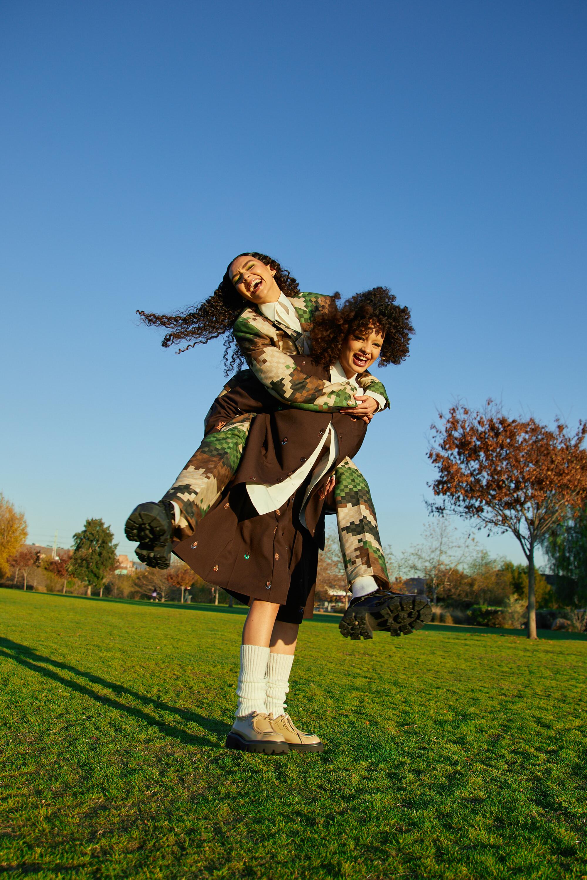 Two models hug each other in a park.