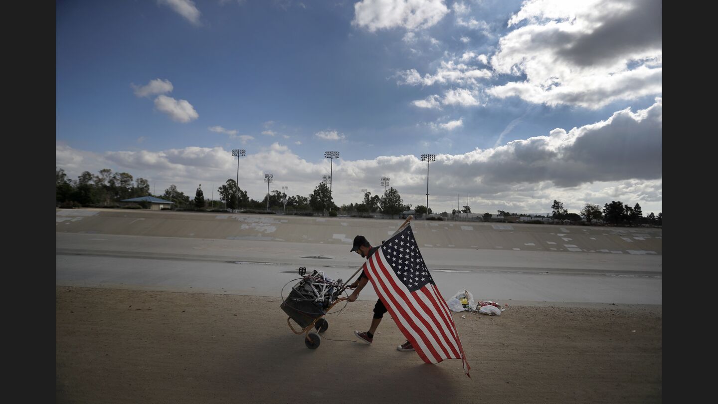 Ivan Reyes moves out of a homeless encampment along the Santa Ana River trail Friday as authories clear the area.