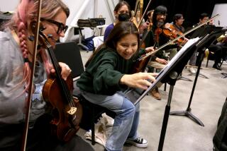 LOS ANGELES, CA - JUNE 5, 2023 - Maya Miguel Hernandez, 14, second from left, enjoys a light moment with Liz Knickerbocker, 31, from left, Linnea Snyder-Straw, 32, and Shine Ling, in his 40s, during a rehearsal with the Heart of Los Angeles Eisner Intergenerational Orchestra (HOLA EIO) at the Arts and Recreation Center in Los Angeles on June 5, 2023. Hernandez is one of the youngest performers with HOLA EIO. HOLA EIO was rehearsing for an upcoming performance for, "Opera Gala Spectacular." HOLA EIO unities multigenerational musicians from multicultural backgrounds to share the joy of music making and progressing toward a common goal of artistic excellence across a diverse musical repertoire. The musicians range from ages 14 to 76. Artistic Director & Conductor Daniel Suk conducts the orchestra. (Genaro Molina / Los Angeles Times)