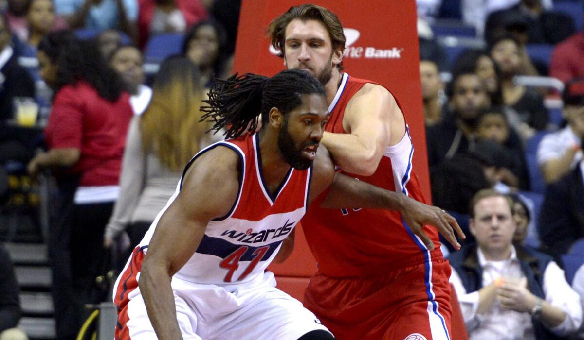 Clippers center Spencer Hawes tries to hold his ground as Wizards power forward Nene drives to the basket in the first half Friday night.
