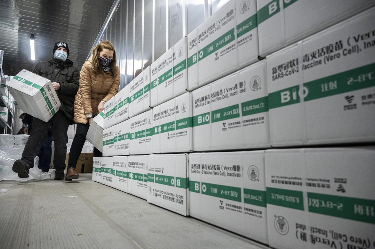 Employees unload the newly arrived coronavirus vaccines from Chinese pharmaceutical company Sinopharm at the logistics base set up to in the parking lot of the government office in the 13th district of Budapest, Hungary, March 3, 2021. (Zsolt Szigetvary/MTI via AP)