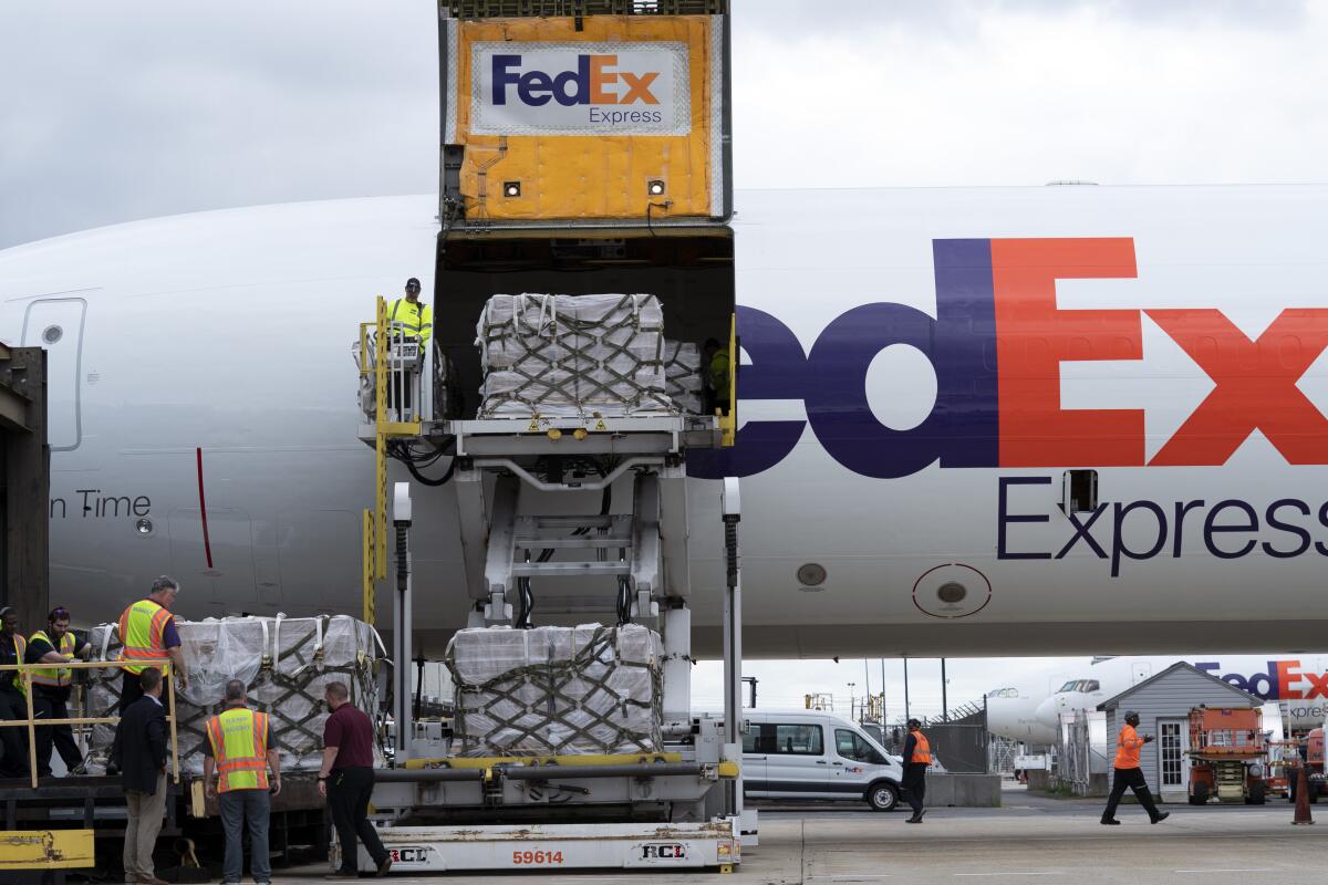 Workers unload a Fedex Express cargo plane carrying 100,000 pounds of baby formula at an airport