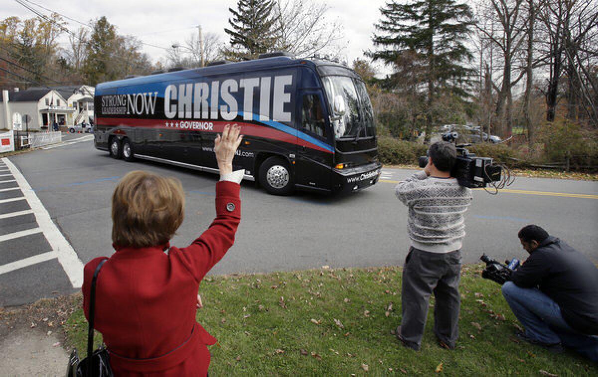 Judy Feldman, 65, waves as a bus carrying New Jersey Gov. Chris Christie passes after he voted in Mendham Township, N.J. The Republican governor is running against Democrat Barbara Buono.