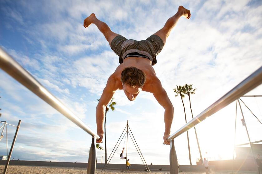Venice, CALIF. - MARCH 19, 2020: Brian Comstock, 29, of Venice does a handstand at Muscle Beach during the Coronavirus pandemic at Venice beach on Thursday, March 19, 2020 in Venice, Calif.. (Jason Armond / Los Angeles Times)