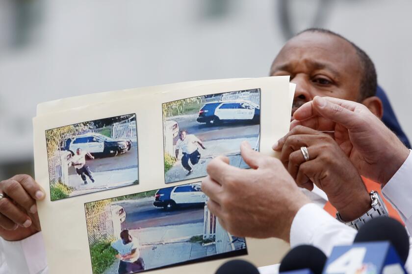 LOS ANGELES , CA - OCTOBER 20: Najee Ali, left, and Cliff Smith, right, point to photographs of Fred Williams Junior who was fleeing a deputy before being fatally shot in downtown on Tuesday, Oct. 20, 2020 in Los Angeles , CA. The family is demanding the body camera footage is released. (Dania Maxwell / Los Angeles Times)