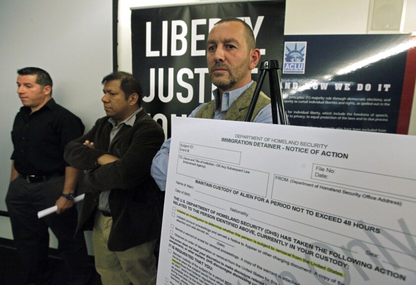 Lead plaintiff Duncan Roy, right, appears at a news conference to announce a federal lawsuit by the American Civil Liberties Union on behalf of arrestees who say they were denied bail because they had federal immigration holds, in Los Angeles.