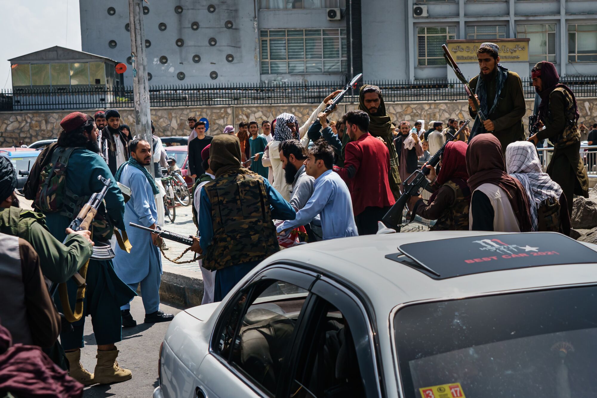 Taliban confront and push people as they try to control the crowd.