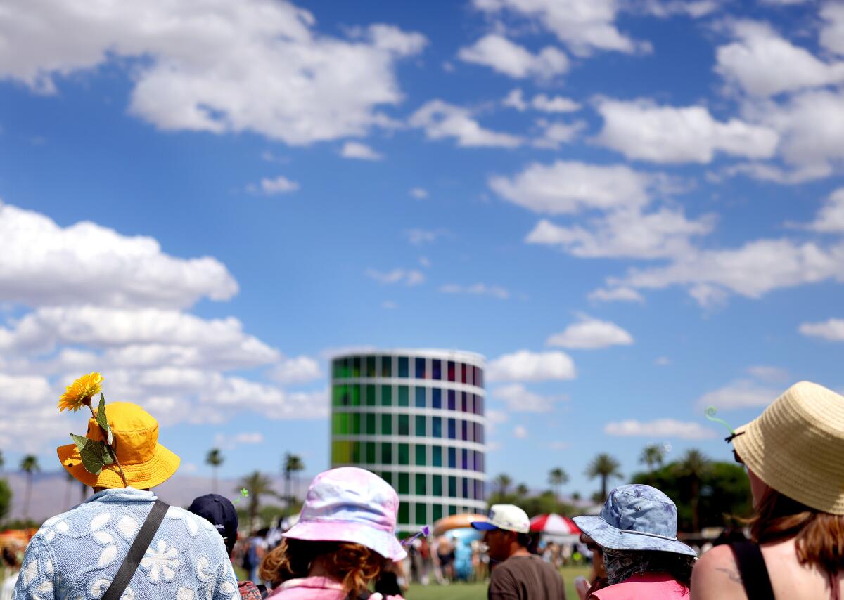 People walk in front of a rainbow tower Spectra at Coachella