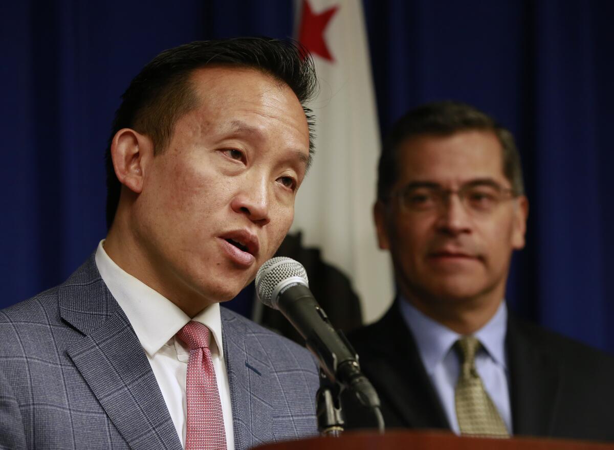 David Chiu speaks into a microphone as Xavier Becerra looks on in 2018