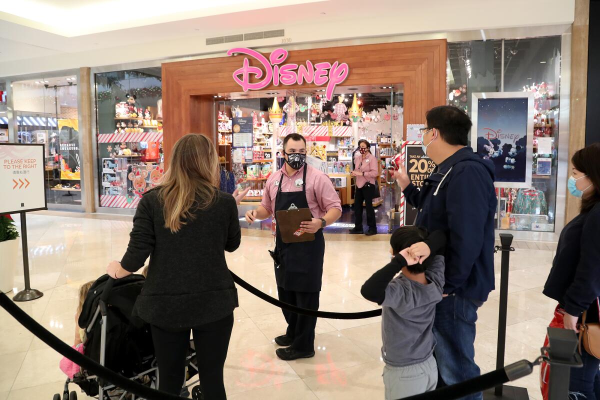 A Disney store employee answers questions as Black Friday shoppers wait in line at South Coast Plaza.