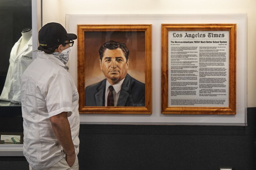 LOS ANGELES, CA - JULY 24, 2020: Robert Lopez, Executive Director for Communications and Public Affairs at Cal State University Los Angeles and a former Los Angeles Times reporter looks at a painting of former Los Angeles Times reporter Ruben Salazar and a copy of his last story, published on August 28, 1970, the day before he died, on display inside Ruben Salazar Memorial Hall, located on the campus. Salazar was killed in 1970 by a tear gas projectile fired by a Los Angeles County Sheriff's deputy. (Mel Melcon / Los Angeles Times)