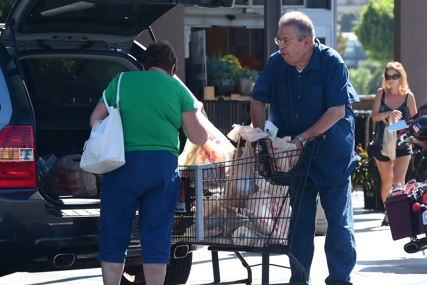 Shoppers transfer groceries from a supermarket cart into their car in Monterey Park, California in September.
