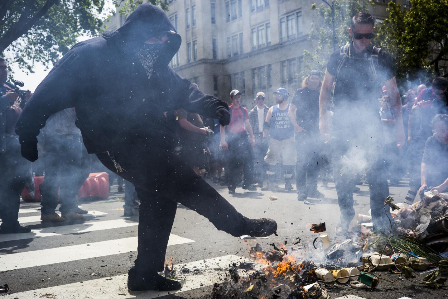 A protester kicks trash removed from a can and set on fire during a pro-Trump rally Saturday in