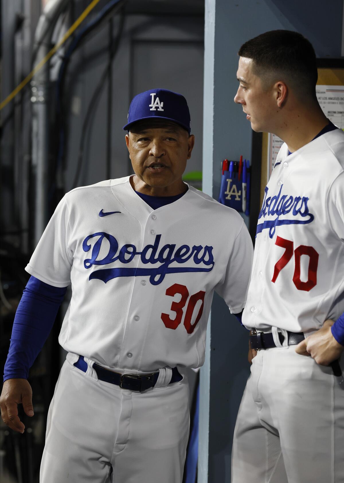 Dave Roberts talks to Bobby Miller in the dugout.