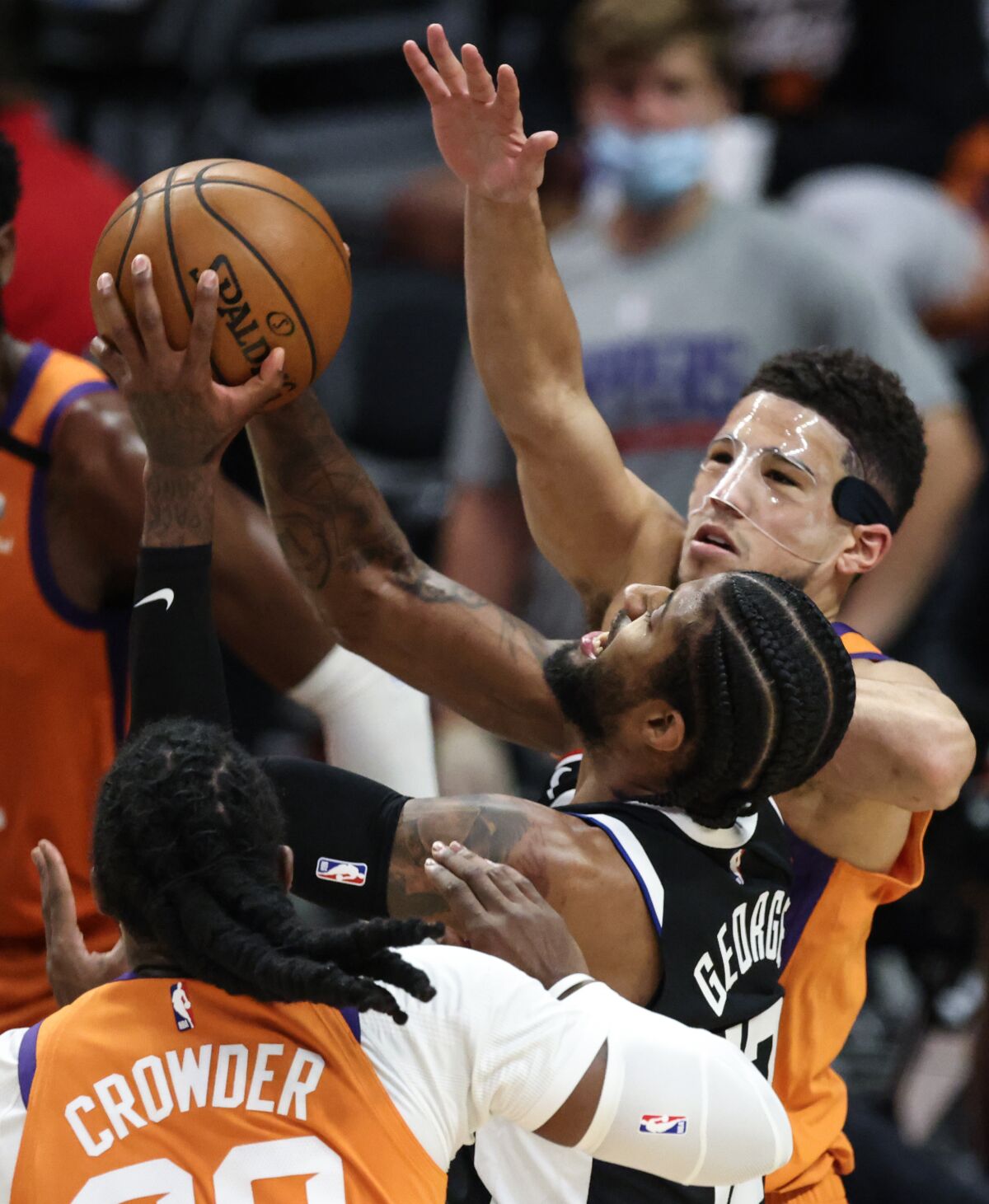 Clippers forward Paul George tries to power his way to a shot against Phoenix's Devin Booker and Jae Crowder.