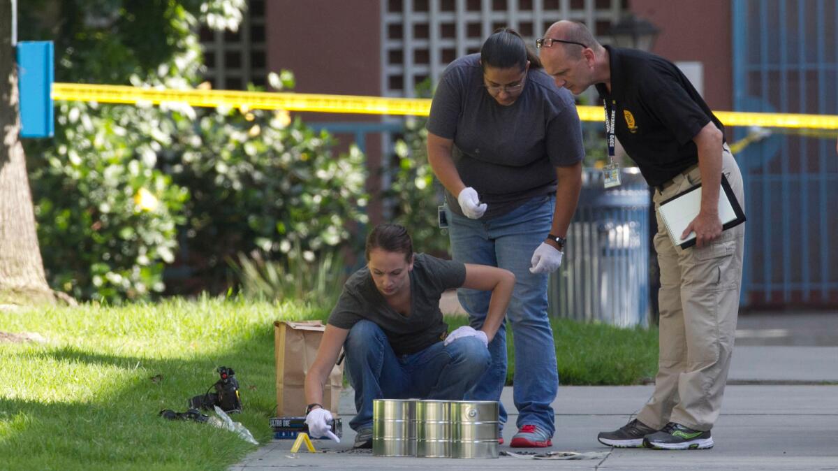 San Diego police investigators gather evidence from the sidewalk and grassy area where a homeless person was attacked in downtown San Diego on July 6.