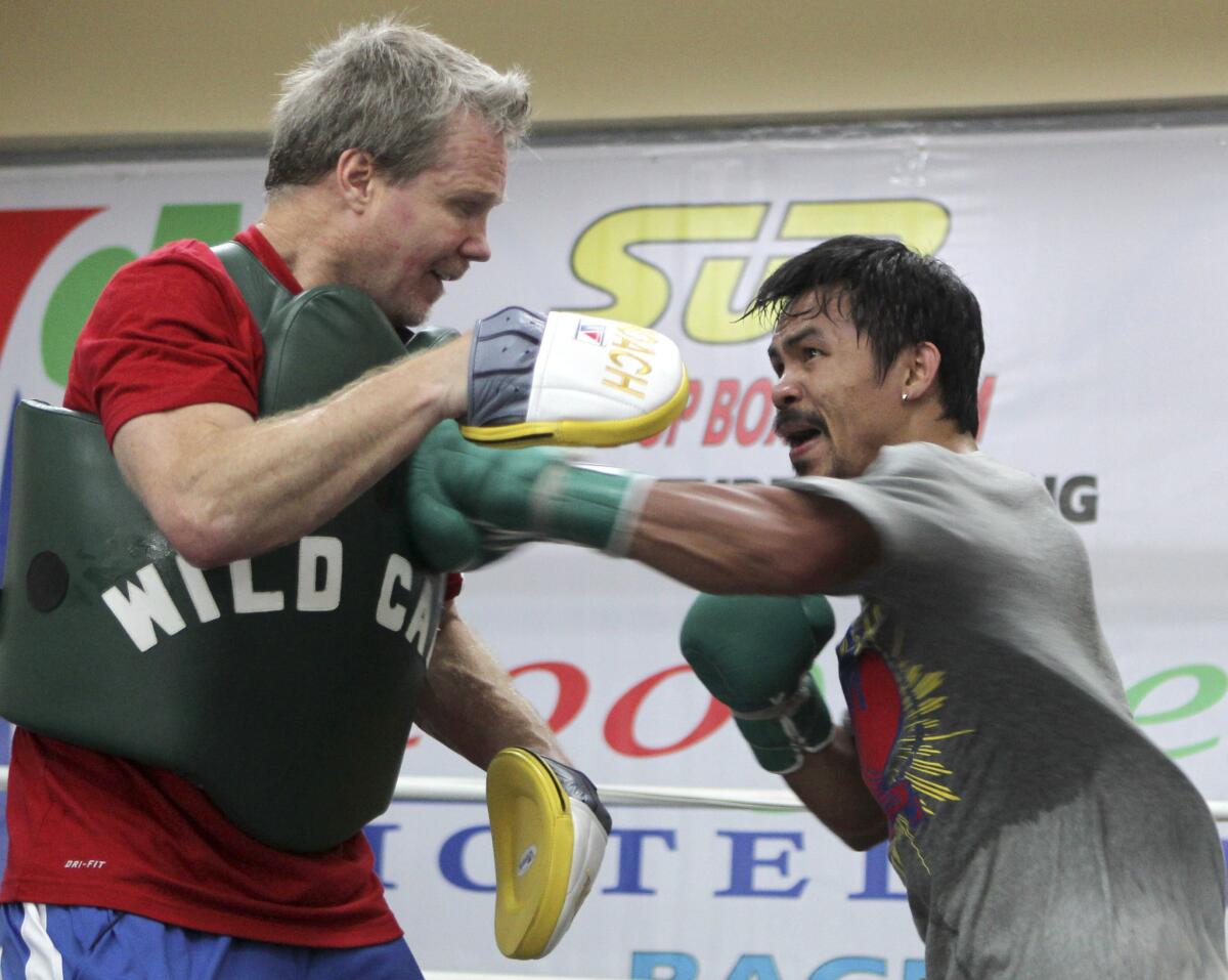 Manny Pacquiao, right, connects to the chest of trainer Freddie Roach during a workout in northern Philippines in March.