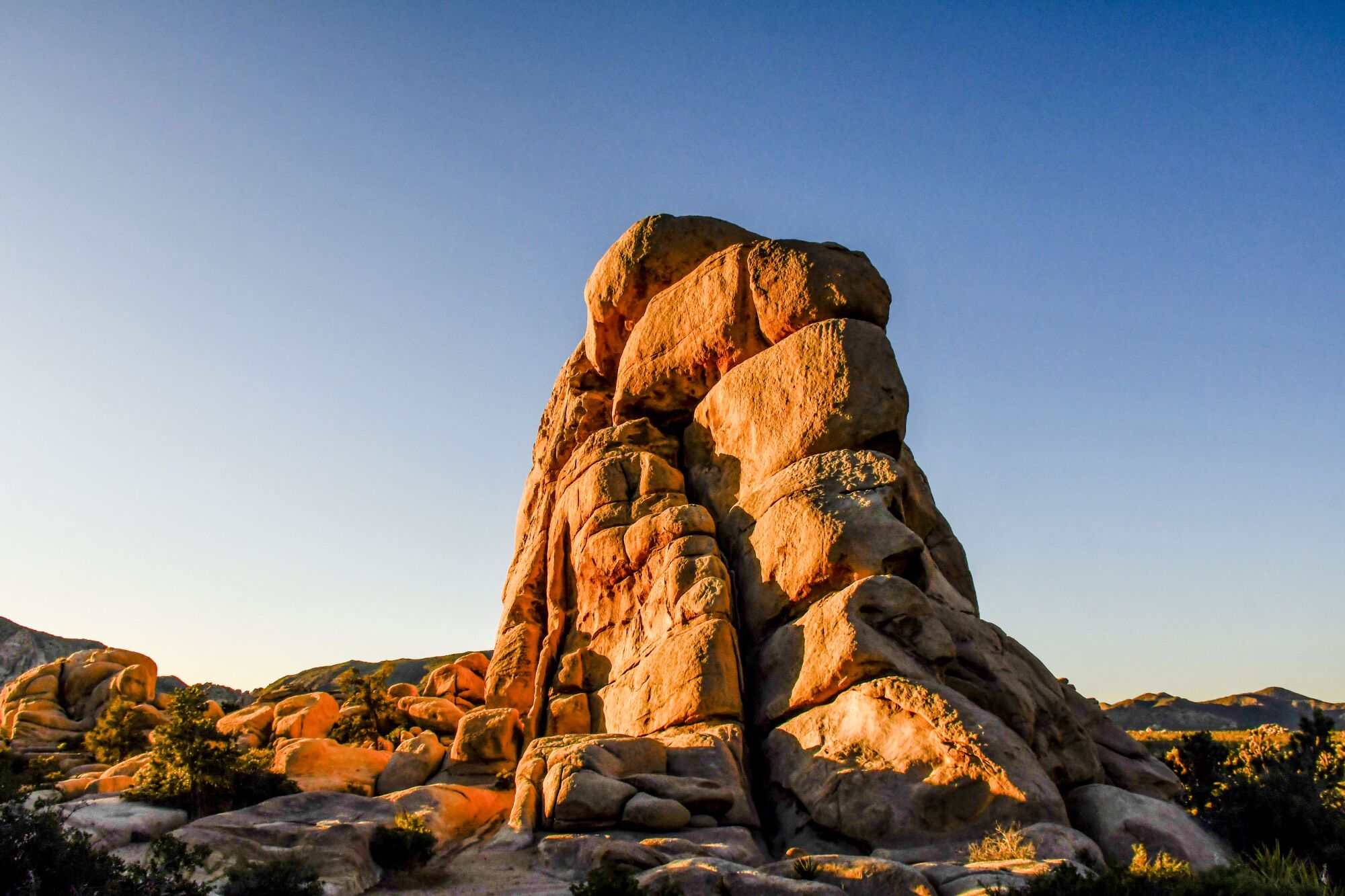 Reddish boulders stand out against a blue sky.
