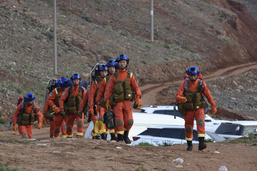 FILE - In this May 23, 2021, file photo provided by China's Xinhua News Agency, rescuers walk into the accident site where over a dozen cross-country marathon runners died in Jingtai County of Baiyin City, northwest China's Gansu Province. Police in western China say a top county official appears to have jumped to his death amid a probe into the deaths of 21 runners last month after freezing rain and strong winds hit the mountain on which they were competing in an ultramarathon. (Fan Peishen/Xinhua via AP, File)