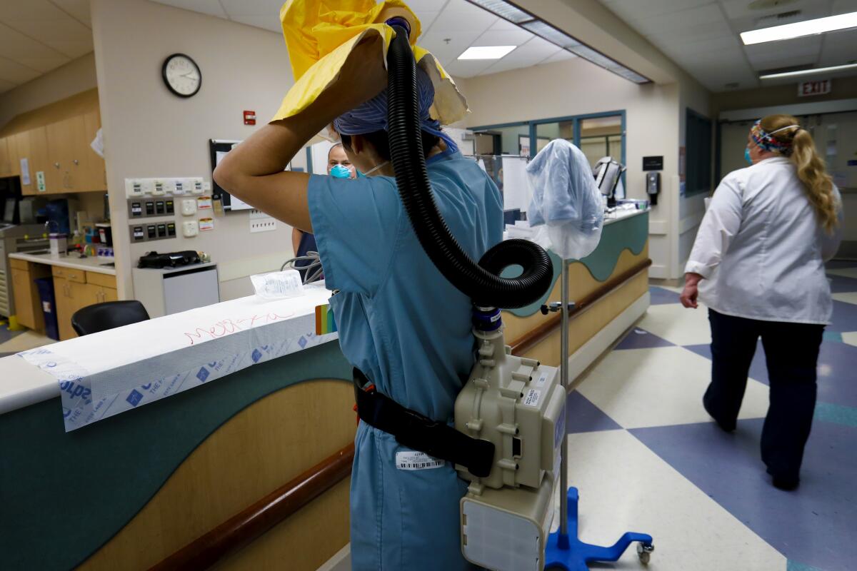 At El Centro Regional Medical Center, physician assistant Celine Sledge puts on her PPE before seeing a COVID-19 patient.