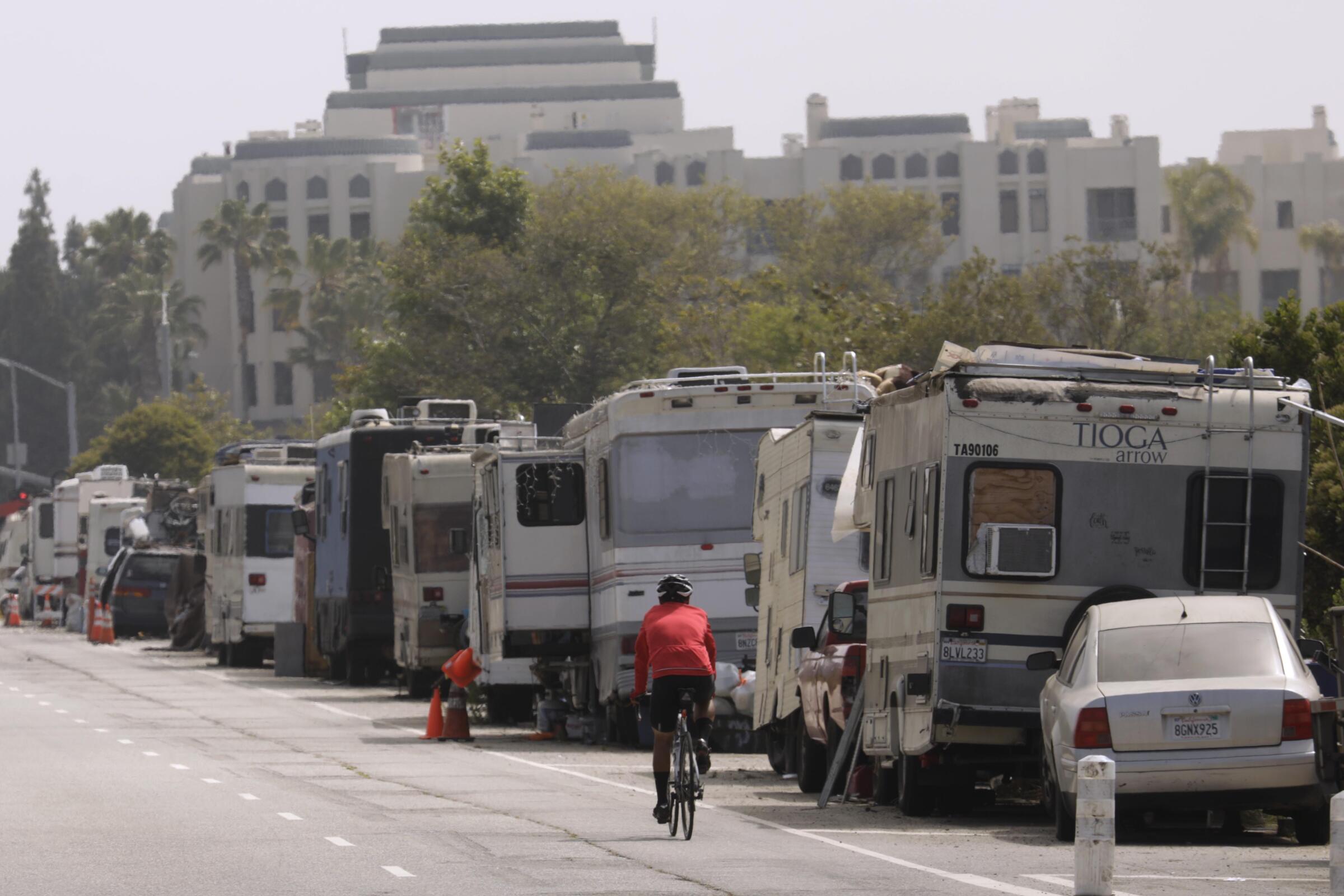 A row of parked RVs and cars on a street.