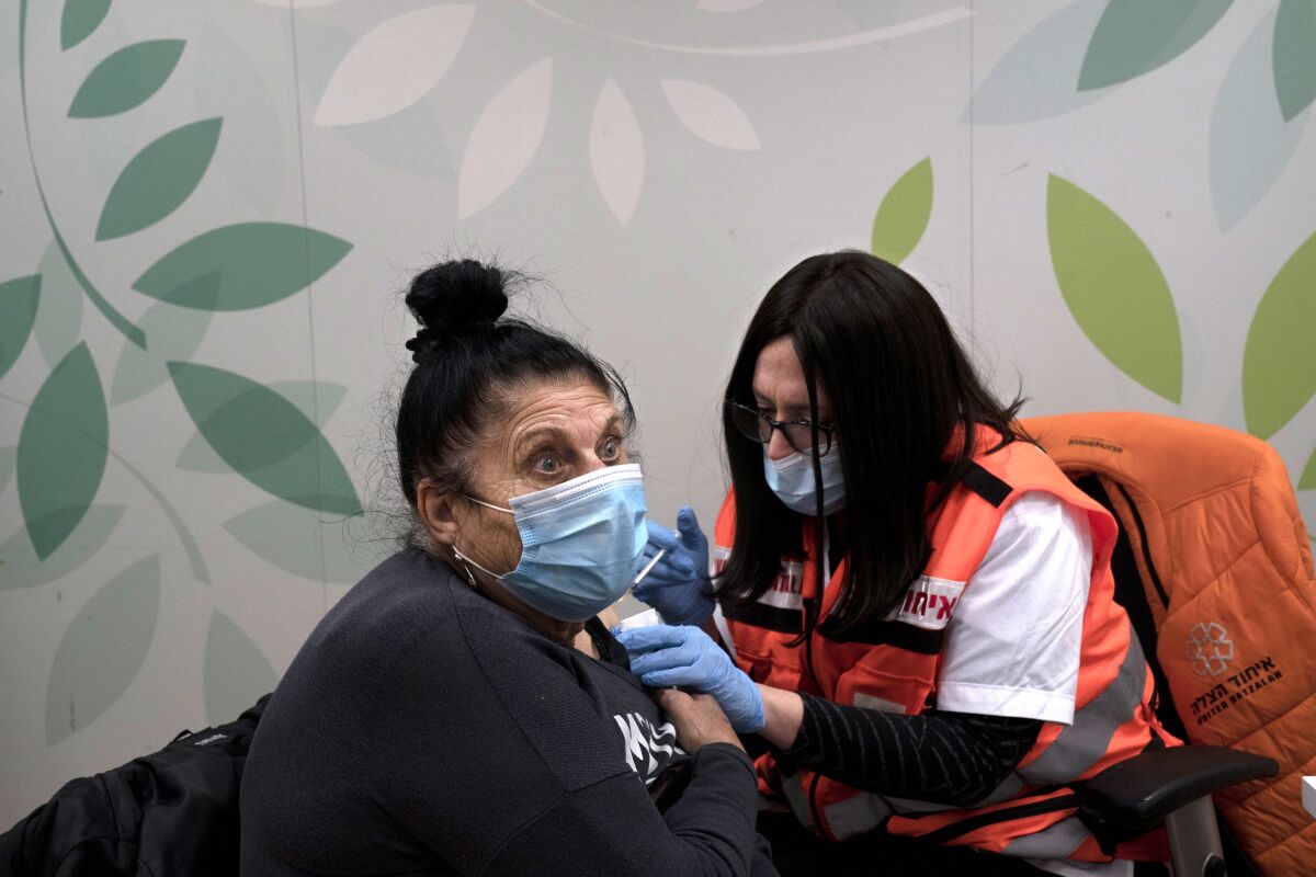 Esther Pamensky, a volunteer with the women's unit of United Hatzalah emergency service, administers a fourth dose of the COVID-19 vaccine to a woman at Clalit Health Services in Mevaseret Zion, Tuesday, Jan. 11, 2022. (AP Photo/Maya Alleruzzo)