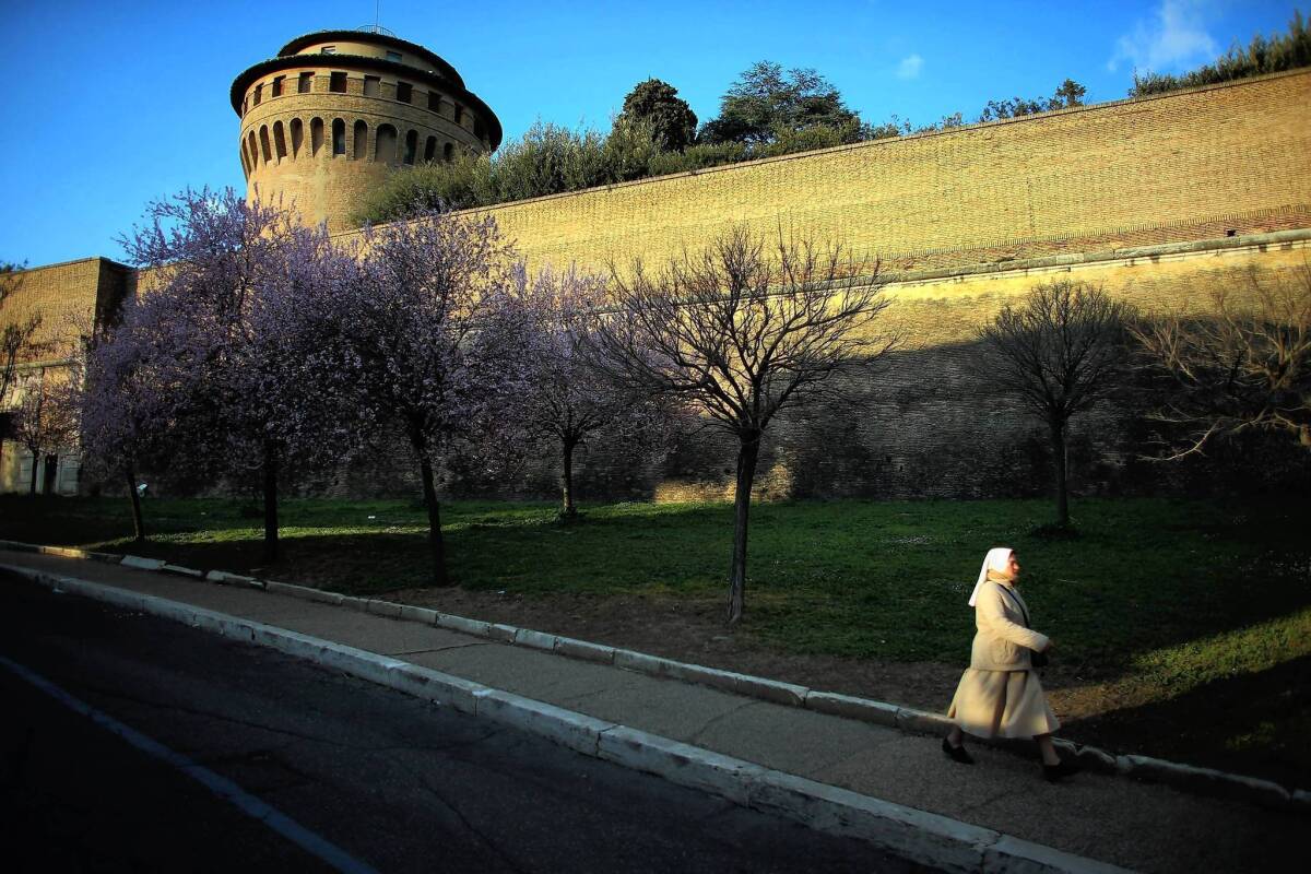 A nun walks along the outer wall of Vatican City, which will soon be home to two popes: Francis and Benedict XVI, who has taken the title of pope emeritus.