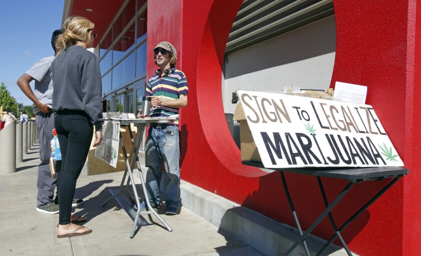 Petition signature gatherer Peter Keyes, right, discusses a petition to legalize marijuana, in Sacramento, Calif.
